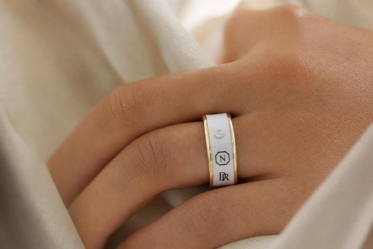 Nodia Ring in fine ceramic resting on linen beside a jeweller's loupe, its engraved sequence visible in grazing light
